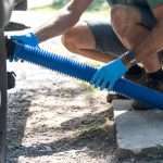 How to Fix a Clogged RV Toilet 10 A person connecting a sewer hose to the RV