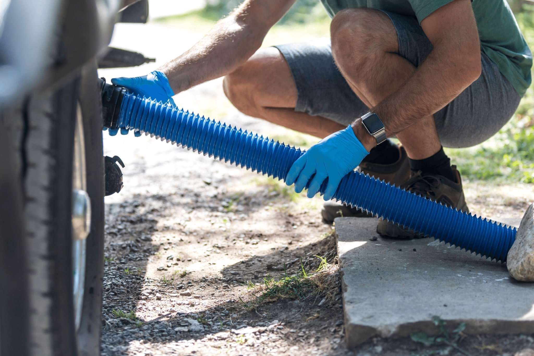 A person connecting a sewer hose to the RV