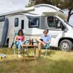 Couple sitting outside of the RV in the Camping chairs