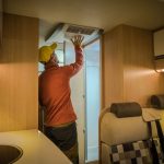 Man inspects RV Air Conditioner Cover
